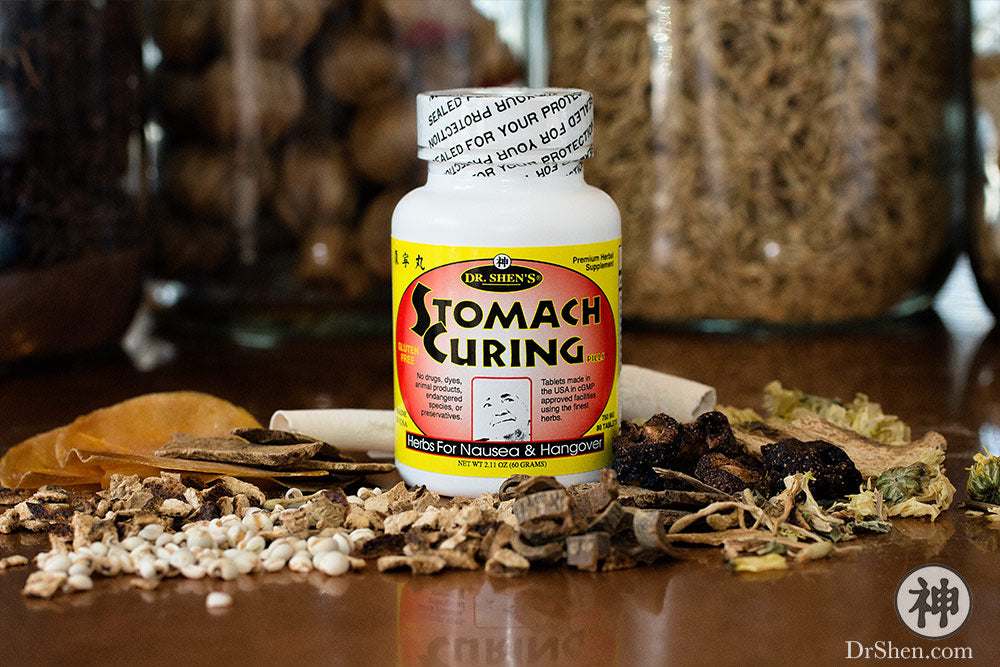 Bottle of Stomach Curing Pills surrounded by raw Chinese herbs